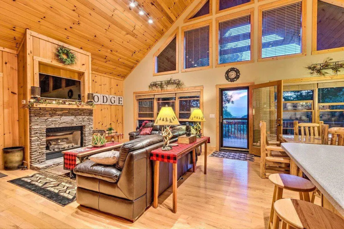 A warm, welcoming dining area with a fireplace as the centerpiece, large windows that reveal sweeping mountain views, a dining table set for meals, and decorative lamps enhancing the cozy mood. The view outside blurs the line between indoors and nature, while the fireplace adds a gathering point for relaxation and storytelling.