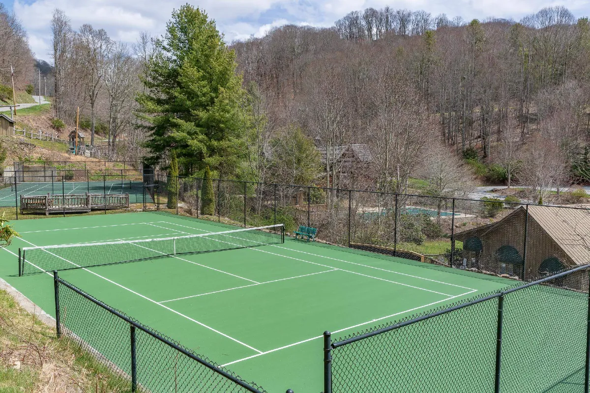 Outdoor tennis courts with surrounding greenery and benches provide an energetic space for friendly matches or enjoying the scenic views after a game. The courts are set in a vibrant and active environment.